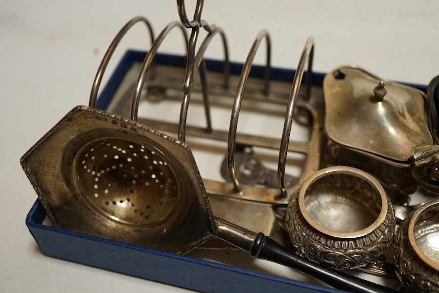 A George V silver sugar caster, Sheffield, 1914, Walker & Hall, together with a four division toast rack, a five peice Edwardian cruet set a/f, a pair of Indian Cutch salts, pair engraved napkin rings, Victorian fiddle,